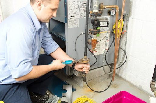 A furnace technician repairing and providing maintenance to a residential heating system in Battlefield, MO. A furnace repair service by an HVAC expert.