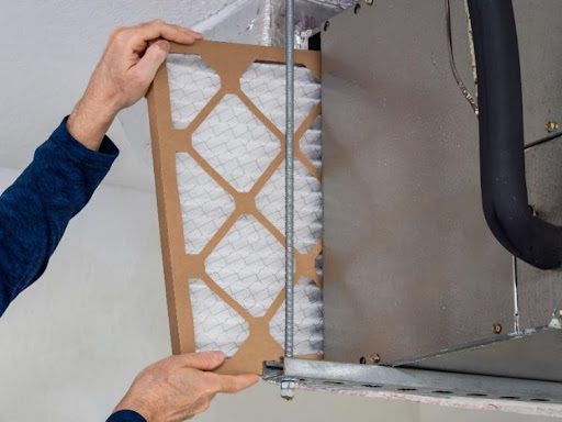 An HVAC technician in Battlefield, MO, installing a brand-new air filter for a residential furnace during a furnace maintenance service.