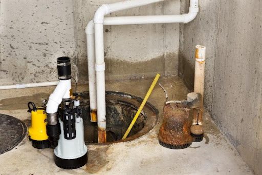 A sump pump being installed by a plumber in a residential basement in Fremont Hills, MO with white pipes.