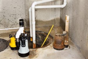 A sump pump being installed by a plumber in a residential basement in Marionville, MO with white pipes.