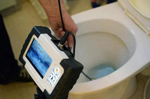 A plumber using camera drain inspection equipment to see what is clogging a residential toilet in Springfield, MO.