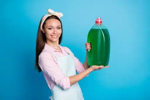 A young female homeowner holding up a large container of dish soap in Springfield, MO. It is important to use the right product and the right amount to avoid flooding your dishwasher or kitchen.